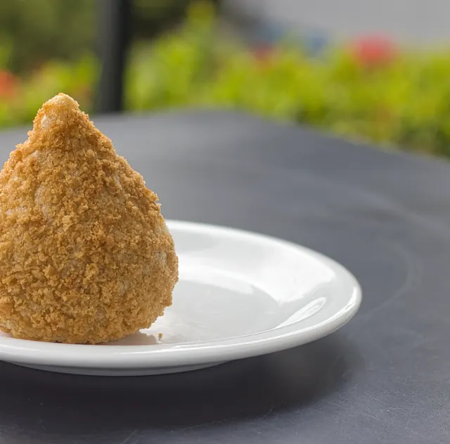 Coxinha dourada sobre prato branco